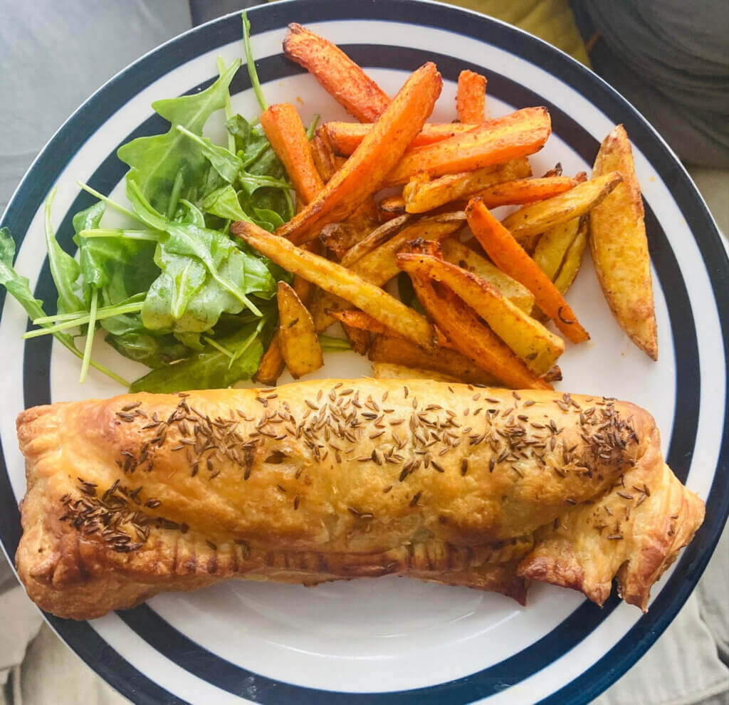 Golden sausage roll with carrot and potato chips and a rocket salad